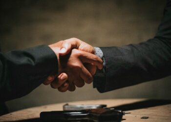 two people shaking hands over a wooden table