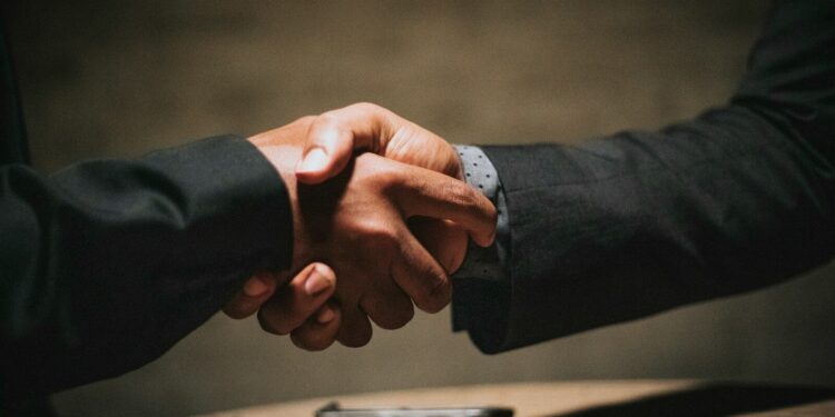 two people shaking hands over a wooden table